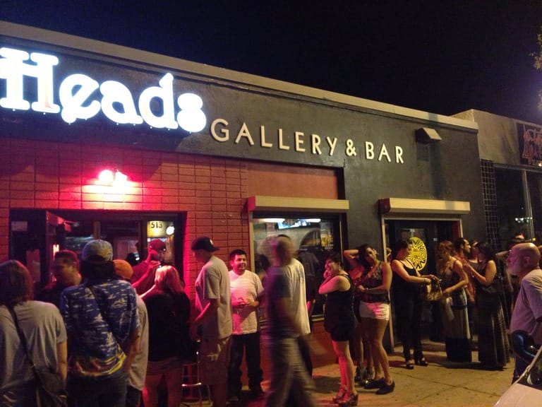 People lined up outside a gallery bar at night.
