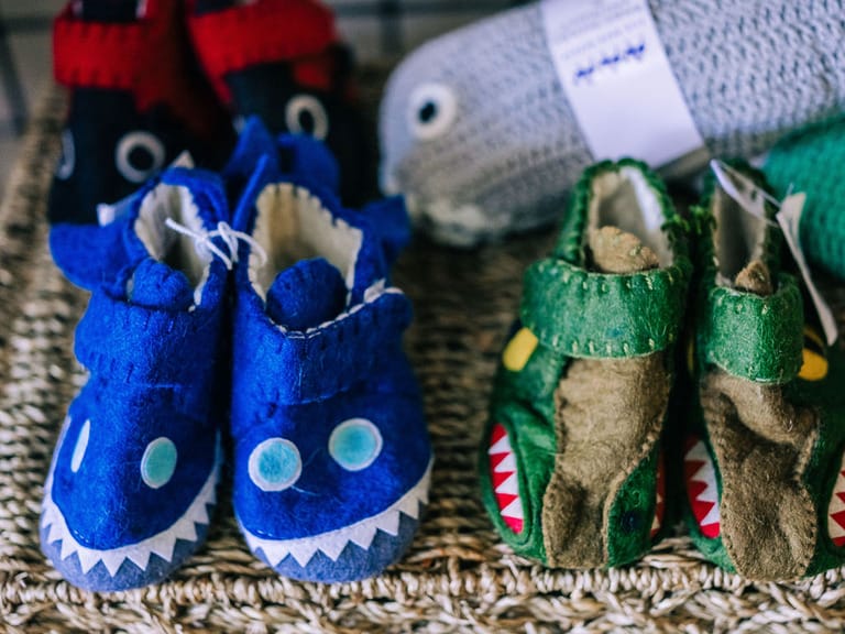 Colorful animal-themed baby shoes on display.