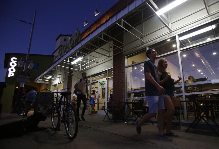 People walking outside a lit storefront at night