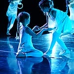 Children performing a dance in blue lighting.