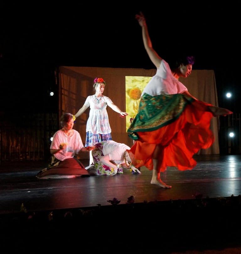Four dancers performing on stage in colorful costumes